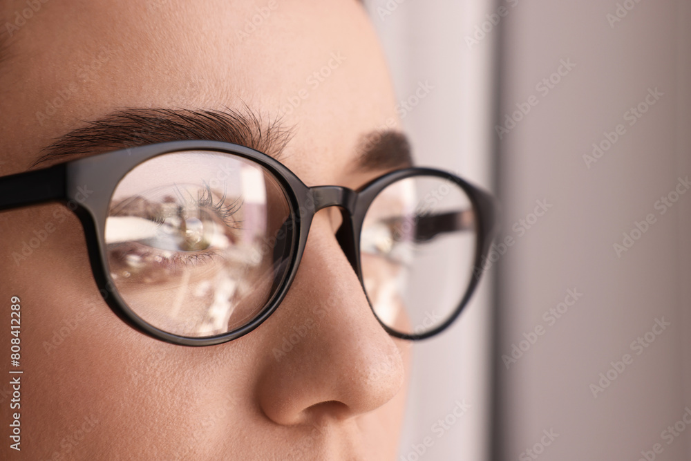 Sticker Woman wearing glasses on blurred background, closeup