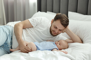 Father with his cute baby on bed indoors