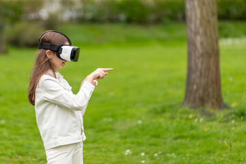Girl in virtual reality headset pointing in a park