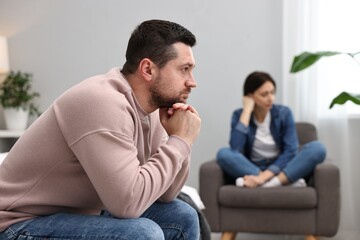 Offended couple ignoring each other after quarrel in bedroom, selective focus. Relationship problems