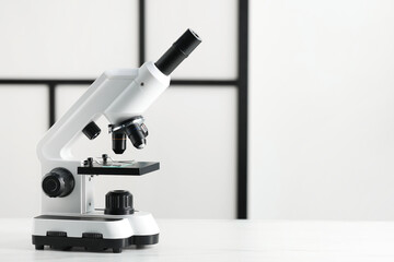 Modern microscope on white table, space for text