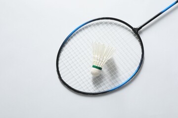 Feather badminton shuttlecock and racket on gray background, top view. Space for text