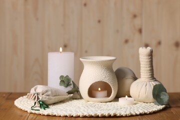 Different aromatherapy products, burning candles and eucalyptus leaves on wooden table