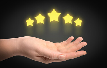 Woman holding virtual stars on black background, closeup. Customer satisfaction score