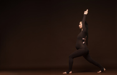 pregnant woman performs demonstrates doing yoga exercises.pregnant nice woman in brown sports...