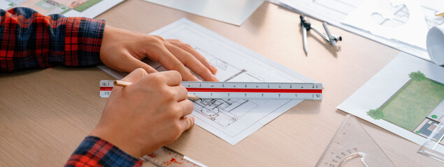 Closeup of architect engineer hand using ruler to mature and draw a blueprint on meeting table with...
