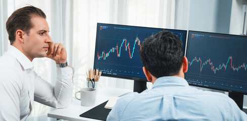 Stock exchange traders discussing on market stock comparing with two screen in chart on panorama...