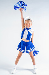 Smiling young cheerleader in a blue and white uniform holding up a pompom above her head
