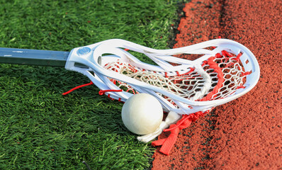 Lacrosse stick on the turf next to a ball close to the track