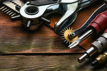 Leather craft work tools and leather on the tanner workbench concept background.