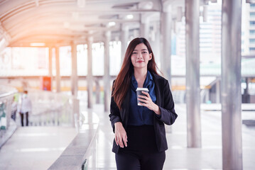 Young Asian Businesswoman holding coffee cup drinking walking on street city outdoor. Women smiling Relax holding take away coffee cup go to work. Women enjoy drinking coffee together in modern city