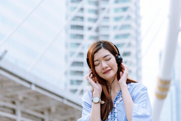 Happy asian dancing woman use headphones listen to music from smartphone happy dance in living room at home. Music mental therapist relaxation woman. Cheerful wellness women dance exercise wellbeing