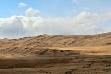 A ridge of high winding hills on the edge of the autumn steppe on a sunny day.