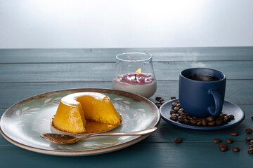 Small quindim, traditional Brazilian sweet, next to a spoon, coffee cup and a candle_8.