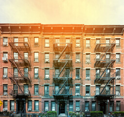 Block of classic old brick apartment buildings with windows and fire escapes in New York City