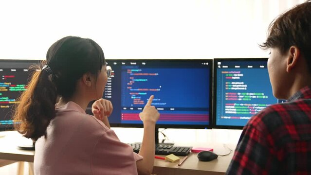 Slow motion back end software developer engineer for computer programming working together on debugging writing computing code, solving complex algorithms display on monitor in office. Burgeoning