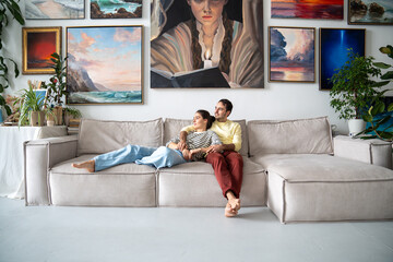 Peaceful couple spouses artists relax in house studio. Smiling man, woman hugging while sitting,...