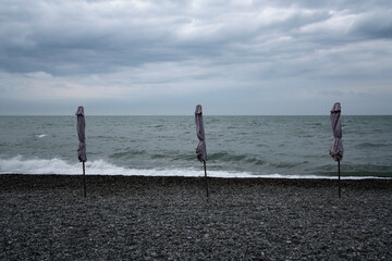 A deserted beach with umbrellas on the Sochi coast against the background of the Black Sea, Adler, Krasnodar Territory, Russia