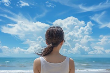 Obraz premium 海を見ている日本人女性の後ろ姿（ビーチ・青空・旅行・休暇）