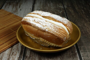 Baked bun filling with soft vanilla cream serving on the plate. Famous soft bread serving in the bakery shop.
