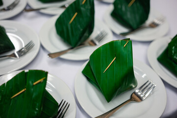 Thai dessert wrapping with fresh banana leaf on ceramic saucer prepared for served breaks between seminars