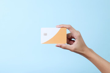 Female hand hold a white blank credit card for mockup. Modern way of banking and buying.