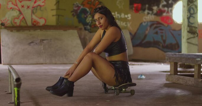 With a skateboard in hand, a girl in a mini skirt explores an indoor skate park.