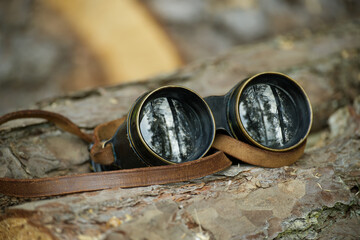 Aged binoculars with a leather strap resting in forest setting