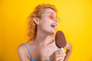 Happy young woman with delicious ice cream in waffle cone on yellow. Woman with a cornet ice cream....