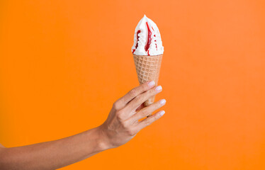 Gelato ice cream cone. Ice cream cone isolated on orange. Summer vanilla taste. Woman holding the...