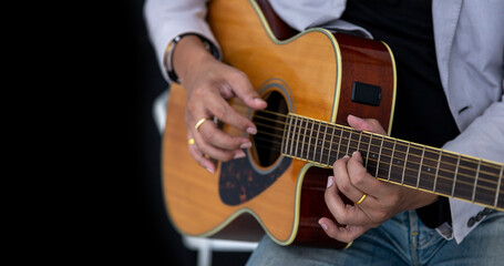 Close up shot of guitarist playing acoustic guitar on black background with copy space for folk music and unplugged performance concept