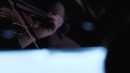 A close-up of the violinist's hands playing the instrument masterfully. A man playing the violin in a dark hall. A soloist in a symphony orchestra