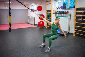 Training in the gym for the figure correction. Young woman doing fitness exercises at gym.