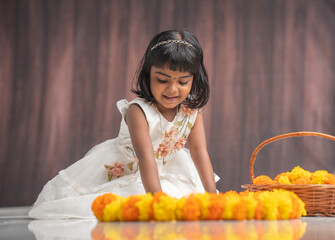 Indian festival special image cute little girl making flower decoration, Kerala Onam festival Pookalam image