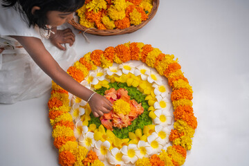 Little girl making Onam Pookalam with fresh flowers, Happy Onam background