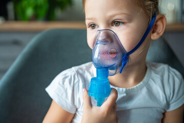 Close up view of little girl are sitting and holding a nebulizer mask leaning against the face, airway treatment concept