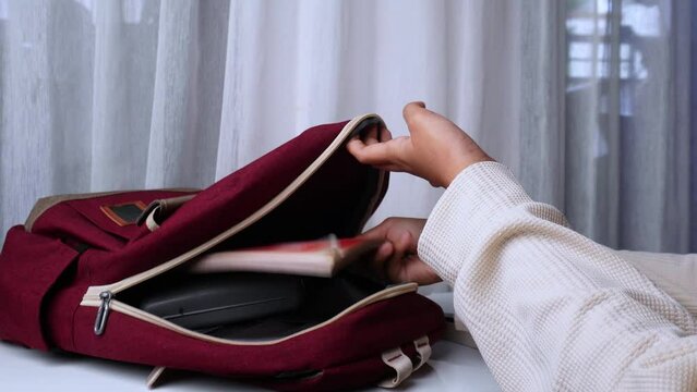 hand person putting books and other stuff in the bag
