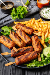 minced beef skewers with potato fries on plate