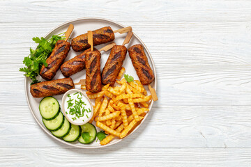 minced beef skewers with potato fries on plate