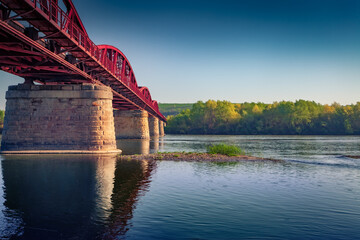 Iron bridge on stone piers across the Dniester River. Picturesque morning scene of Ukrainian...