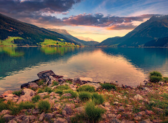 Great summer sunset on Resia (Reschensee) lake with huge mountain peak on background. Resia village...