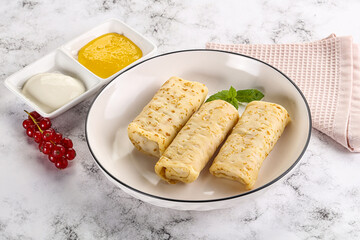 Homemade stuffed pancakes with honey and cream sour
