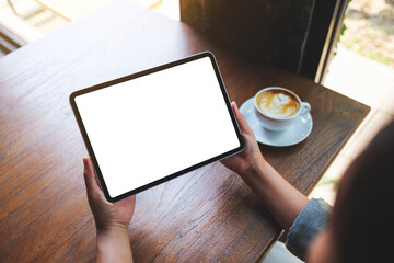 Top view mockup image of a woman holding digital tablet with blank white desktop screen in cafe