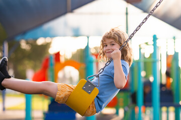 Happy kids having fun on playground. Kid swinging. Happy little child having fun on swing in playground. Cute child swinging on sunny spring day.