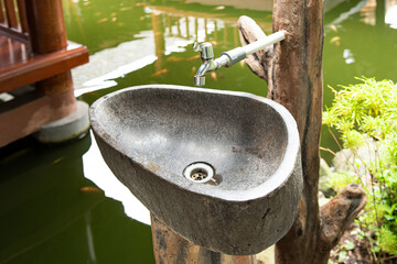 The stone sink for washing hands, which is arranged with natural decorations such as wood and...