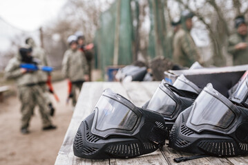 Protective black helmets for paintball lying on wooden table ready for game. Lineup of paintball helmets, ensuring safety during games
