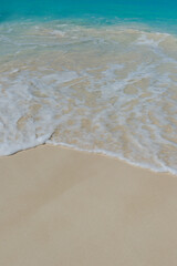 Turquoise water washes ashore on a white sandy beach.