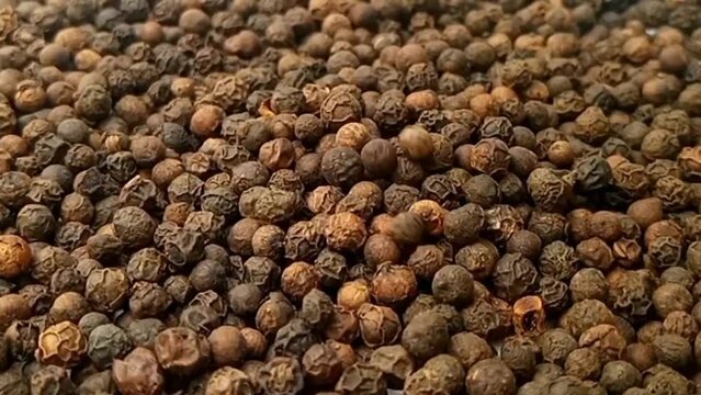 Black pepper fall on rotating full frame background, micro shot, spinning, herbs and spices