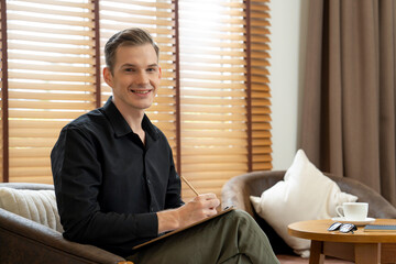 Portrait of happy and smiling male psychologist portrait sitting on arm chair in psychiatrist...
