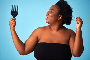 Beauty, comb and black woman with hair care in studio for natural, afro and salon treatment. Cosmetic, health and African female model with brush for curly hairstyle routine by blue background.